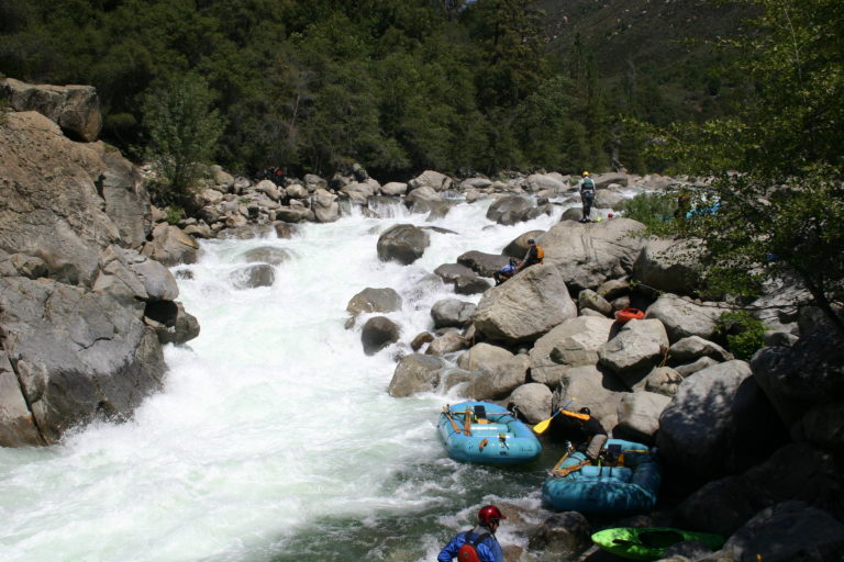 Rafts and kayaks at the bottom of the portage at Lumsden falls on the Upper Tuolumne and Cherry Creek
