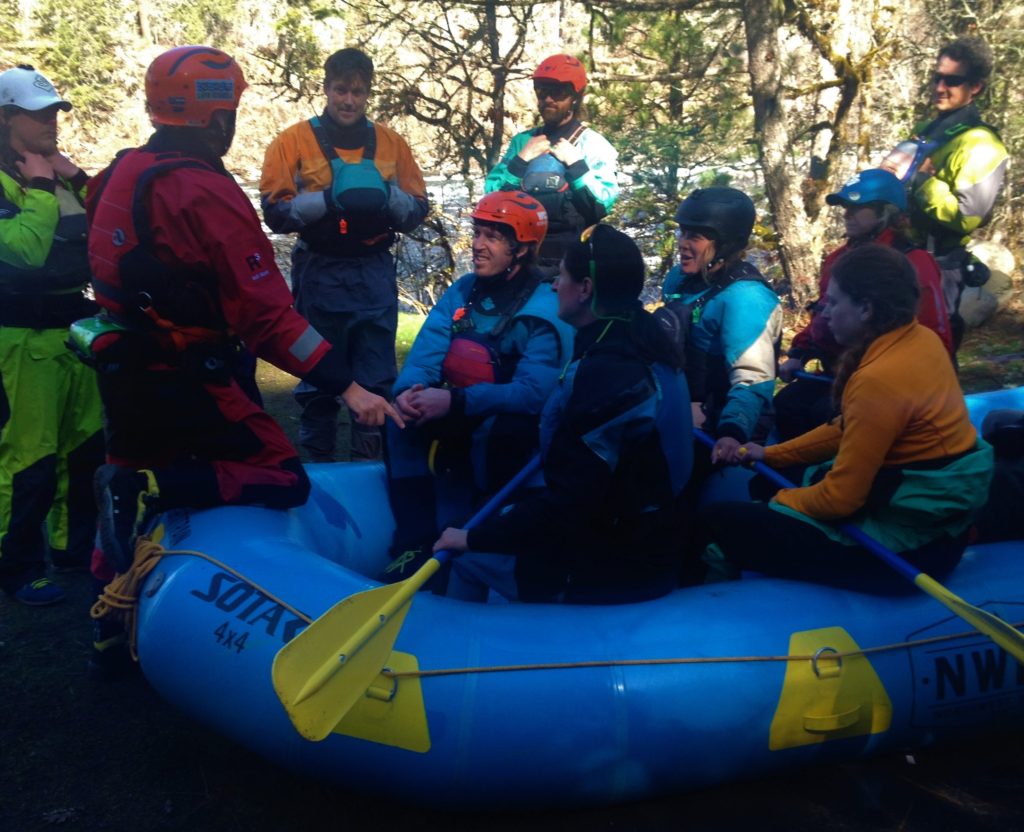Guides teaching whitewater rafting commands to paddle crew