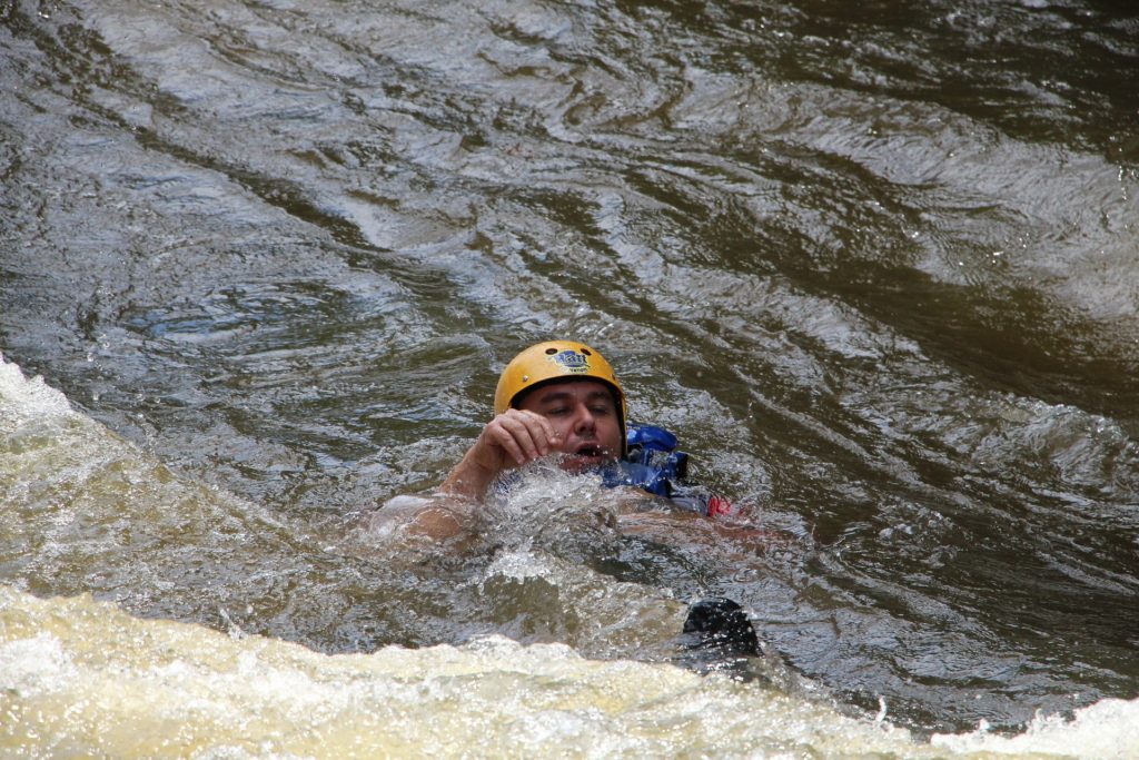 rafter swimming rapid with helmet and life jacket