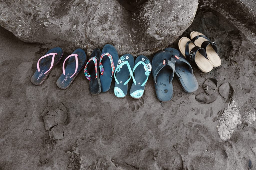 sandals in sand next to a river